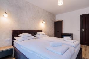 una camera da letto con un grande letto con lenzuola e cuscini bianchi di Pensiunea Doro a Călimăneşti