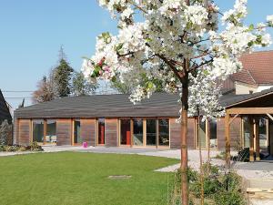 a tree with white flowers in front of a building at Eco-gîte Au Natur'Ailes des Collines in Tournai