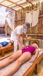 a woman in a spa with a woman laying on a bed at Hotel Jungla y Estrellas in Coba