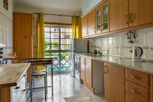 a kitchen with wooden cabinets and a counter top at Casa das Lontras in Faro