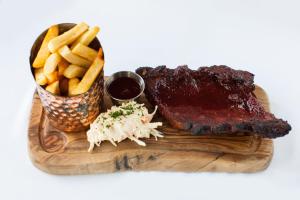 a wooden cutting board with ribs and french fries at Crown Lodge Hotel in Wisbech