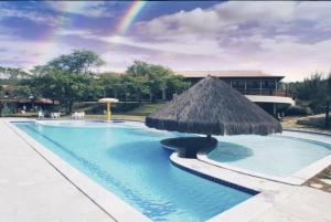 a pool with a straw umbrella and a rainbow at Monte Castelo | Gravatá in Bezerros