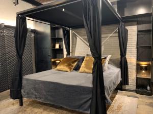 ローマにあるRomantic Wellness Apartment COLOSSEOの黒いカーテンが付いた天蓋付きベッドのある寝室