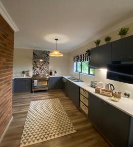 una cocina con armarios negros y una pared de ladrillo en Valley Lakes THE LODGE, en Underberg