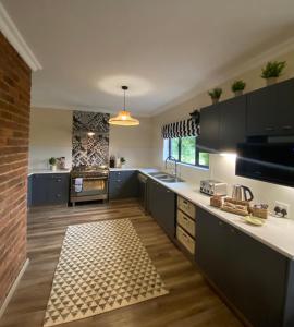 a kitchen with black cabinets and a brick wall at Valley Lakes THE LODGE in Underberg +27 photos