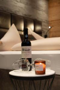 a bottle of wine and a candle on a table next to a bed at The VIEW - KAPRUN in Kaprun