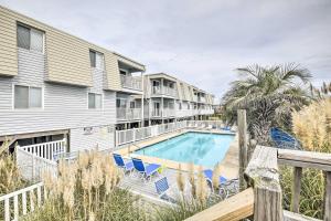 a balcony with a pool and chairs and condos at Cozy Ocean Isle Beach Condo, Steps to the Beach! in Ocean Isle Beach