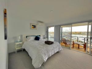 a white bedroom with a bed and a balcony at Marina Reflections in Port Lincoln