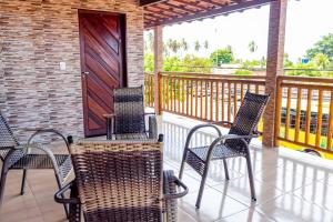 a porch with chairs and a wooden door at Pousada Estrela da manhã in São Miguel do Gostoso