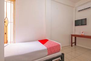 Schlafzimmer mit einem Bett mit einer roten und weißen Decke in der Unterkunft OYO 2562 Pondok Tajlibu Syifa Syariah in Bandung