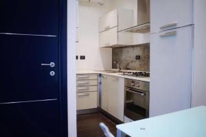 une cuisine avec des placards blancs et une porte bleue dans l'établissement Casa Falco, à Turin