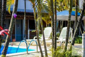 a group of white chairs next to a swimming pool at Minke Chalés in Caraguatatuba