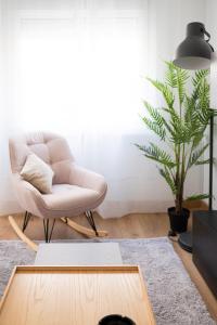 a living room with a white chair and a plant at Expoholidays - General Tamayo PARKING gratis in Almería