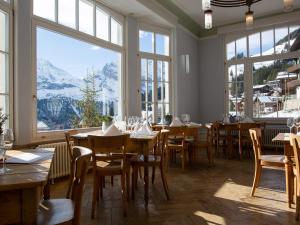 un ristorante con tavoli, sedie e ampie finestre di Hotel Regina a Mürren