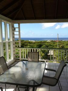 a screened in porch with a table and chairs and the ocean at Joie De Vivre in Charlestown