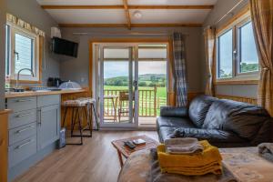 a living room with a leather couch and a kitchen at The Ash Shepod - Smardale Mill in Smardale