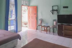 a room with a red door and two chairs and a table at Villa Getsemani Mitra RedDoorz in Sangkanurip