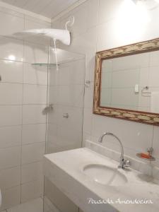 a bathroom with a sink and a mirror and a shower at POUSADA AMENDOEIRA in Búzios