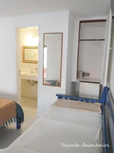 Cama en habitación con espejo y lavabo en POUSADA AMENDOEIRA, en Búzios
