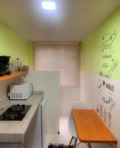 uma cozinha com um balcão, um fogão e uma mesa em LOFT aconchegante no Centro de Macaé, Wifi, Ar condicionado e Cozinha completa em Macaé
