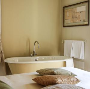 a bathroom with a tub and two pillows on a bed at Spazio[Bianco] in Ivrea