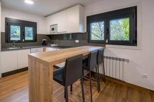 uma cozinha com um balcão de madeira e cadeiras pretas em Finca Bacelo Ribeira Sacra em Sober