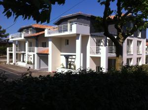 un edificio blanco con balcones y un árbol en Appartement La Villa Gayrou, en Vieux-Boucau-les-Bains