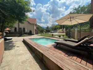 a swimming pool with two lounge chairs and an umbrella at Lodge Zeleni svet in Crni Vrh
