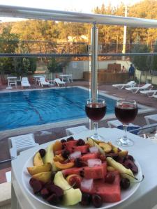 une assiette de fruits sur une table avec deux verres de vin dans l'établissement Mucize Termal Spa, à Pamukkale