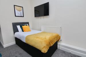 una camera da letto con un letto con una coperta gialla sopra di Cute Studio 4 mins Walk To Planet Ice, Sleeps 3 a Coventry