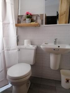 a white bathroom with a toilet and a sink at Damara Beachfront Resort in Baler