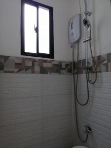 a bathroom with a shower with a toilet and a window at Damara Beachfront Resort in Baler