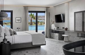 Schlafzimmer mit einem Bett, einem TV und einer Badewanne in der Unterkunft Aeonic Suites and Spa in Mykonos Stadt