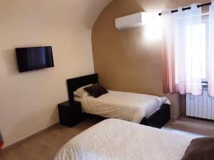 Cette chambre comprend 2 lits et une télévision murale. dans l'établissement Dimora normanna, à Aversa
