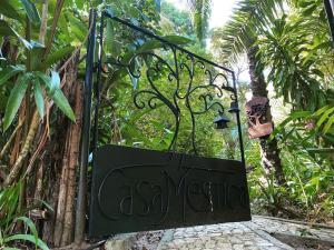 Una puerta a un jardín con un cartel. en Casa Mestiça, en Isla de Boipeba