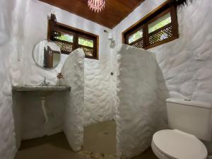 a white bathroom with a toilet and a sink at Casa Mestiça in Ilha de Boipeba
