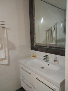 a white bathroom with a sink and a mirror at One bedroom apartment new with large living room in Athens