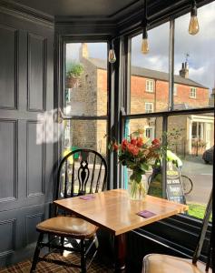 a table in front of a window with a vase of flowers at The Bay Horse, Masham in Masham