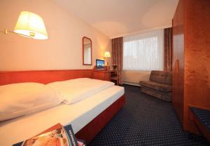 ein Hotelzimmer mit einem Bett und einem Stuhl in der Unterkunft Hotel Seegarten Quickborn in Quickborn