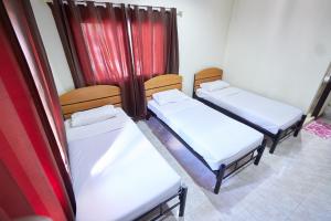three beds in a room with red curtains at Toon Guesthouse in Sukhothai