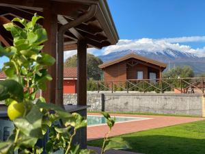 uma casa com um campo de ténis e uma montanha em Agricampeggio Verde Etna em Aci SantʼAntonio