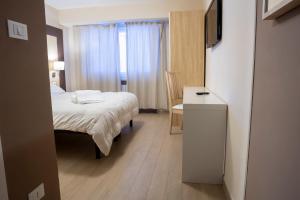 una camera da letto con un letto, una scrivania e una televisione di Hotel Hermitage a Sestriere