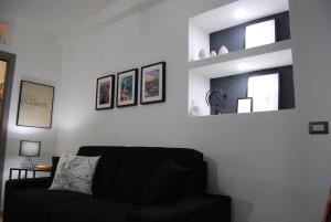ein Wohnzimmer mit einem schwarzen Sofa und einigen Bildern in der Unterkunft Etnea 365 Apartment in Catania