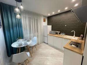 a kitchen with a small table and a kitchen with a sink at Krivenko 49 Str by Slissenko Inn in Pavlodar