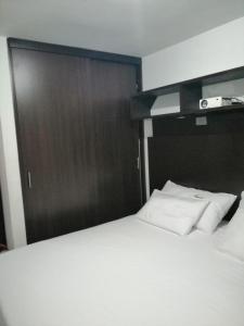 - une chambre avec un lit blanc et un mur en bois dans l'établissement Tu Apartamento en el Eje Cafetero, à Montenegro