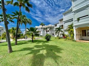a lawn with palm trees in front of a building at Duplex JUNGLE BLEUE Terrasse vue mer incroyable in Marigot