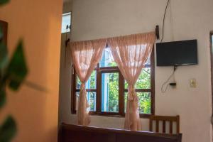 a window with pink curtains and a television in a room at Hotel Rabin Itzam in Lanquín