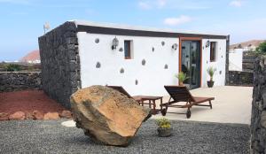 a house with a stone wall and a large rock at Sun, Relax & Lava, Free wifi 600mb, BBQ in Tinajo