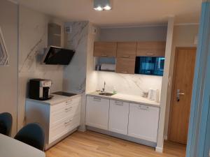 a small kitchen with white cabinets and a sink at Apartament na Kasprowicza in Kołobrzeg