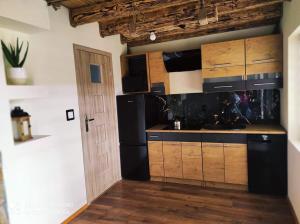 a kitchen with wooden cabinets and a black refrigerator at Domki Wilcze Siedlisko - Bieszczady in Hużele